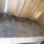 Close-up view of two timber beams joined by metal plates and bolts, with several bolts misaligned and protruding at irregular angles.